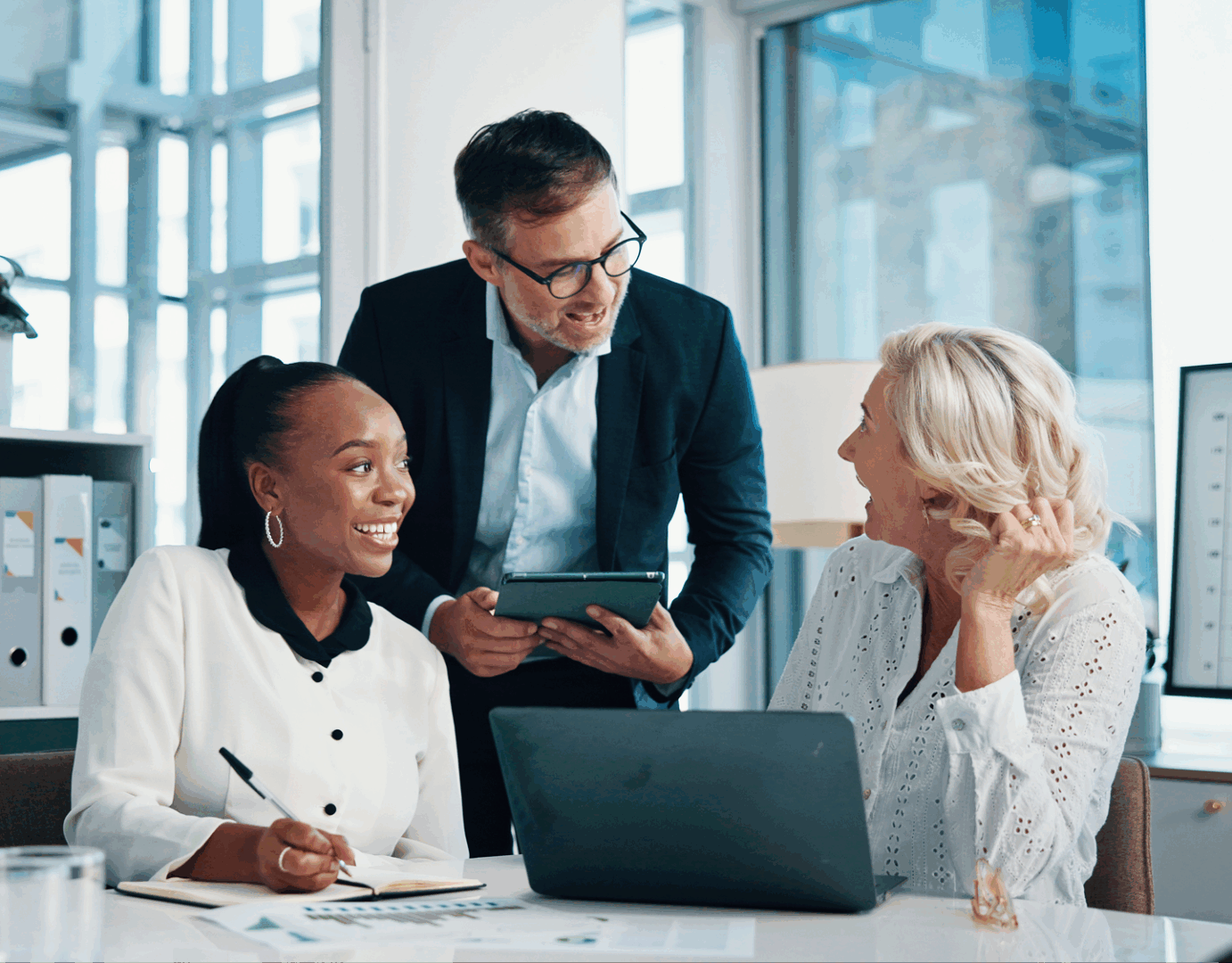 Three colleagues smiling during a meeting.